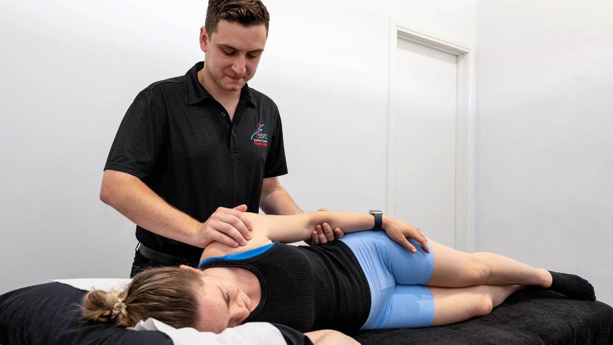 Physiotherapy practitioner in a clinic in Bentleigh East performing adjustments to a young woman athlete to remedy her back and shoulder pain.